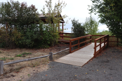 Shelter overlooks wetlands – railings – compact gravel trail with steep grade transitions to wood ramp